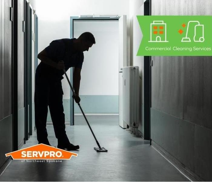Silhouette of a man mopping a hallway floor