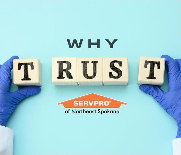 TRUST spelled on wooden tiles with gloved hands with the word why and SERVPRO logo