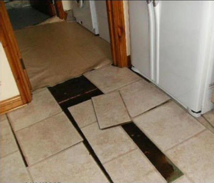 Tile floor with loosened tiles due to water damage